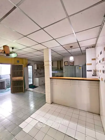 Spacious kitchen with open layout and tiled flooring, featuring modern appliances and ample natural light.