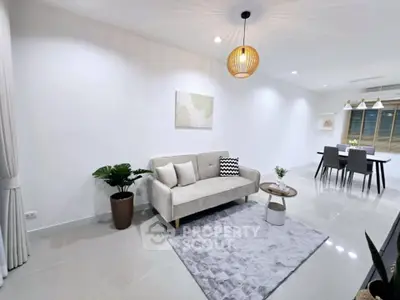 Modern living room with elegant decor and dining area, featuring stylish lighting and cozy seating.