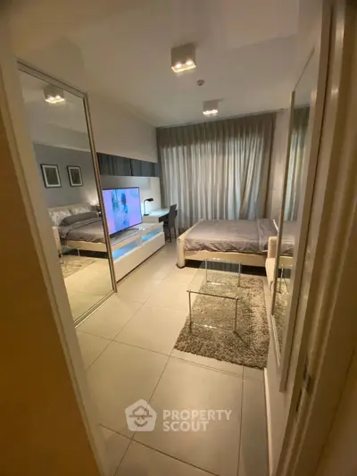 Modern bedroom with stylish decor, mirrored closet, and cozy ambiance in a contemporary apartment.