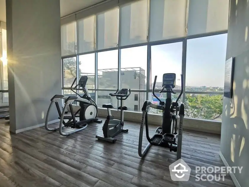 Modern gym with exercise equipment and large windows offering city views