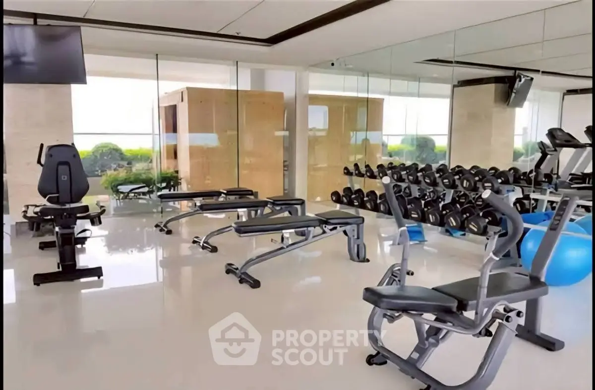Modern gym with state-of-the-art equipment and mirrored walls in luxury building.