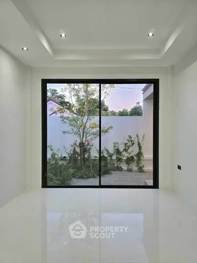 Modern minimalist room with large glass doors opening to a serene garden view.
