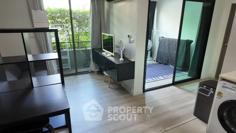 Modern living room with balcony and laundry area, featuring sleek furniture and natural light.