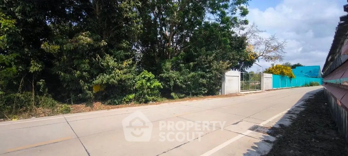 Spacious land plot with lush greenery and secure gated entrance, ideal for development.
