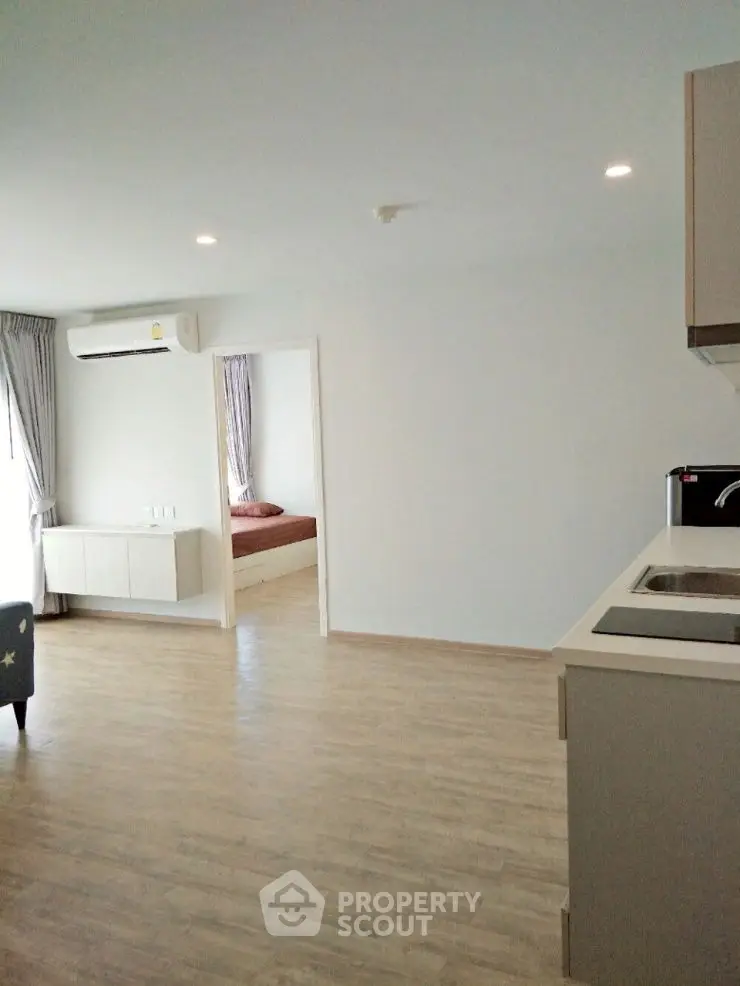 Modern open-plan living area with sleek kitchen and cozy bedroom view.
