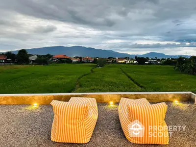 Stunning rooftop view with cozy seating overlooking lush green fields and distant mountains.