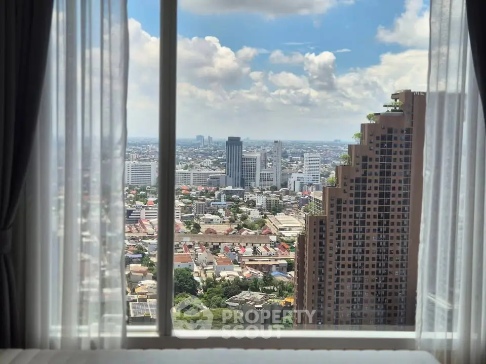 Stunning cityscape view from high-rise apartment window with clear blue sky.