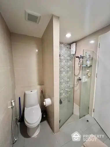 Modern bathroom with glass shower enclosure, neutral tile walls, and sleek fixtures, offering a clean and contemporary living space.