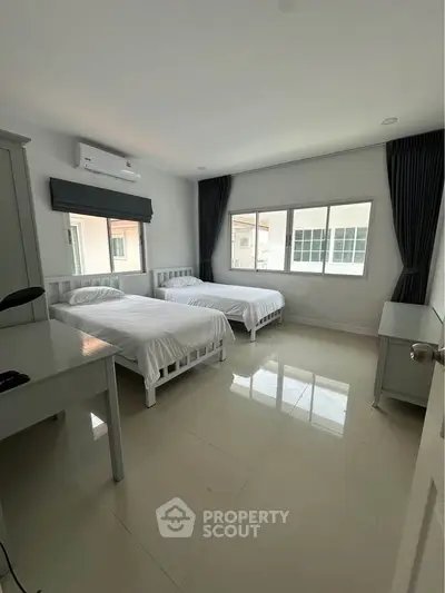 Spacious bedroom with twin beds and large windows in modern home