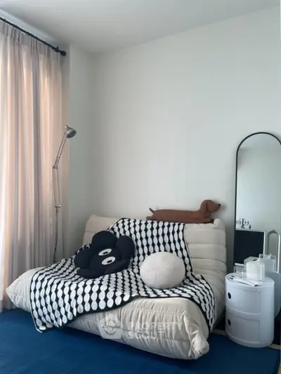 Cozy bedroom with stylish decor and modern furniture, featuring a comfortable futon and elegant floor lamp.