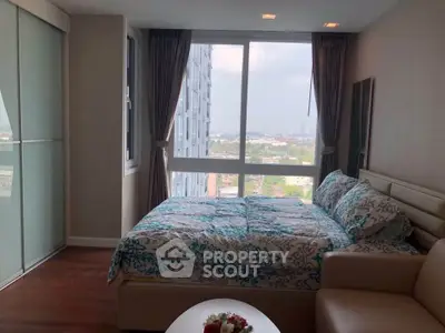 Cozy bedroom with large windows offering a stunning city view, modern decor, and ample natural light.