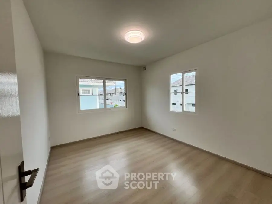 Spacious empty bedroom with wooden flooring and large windows