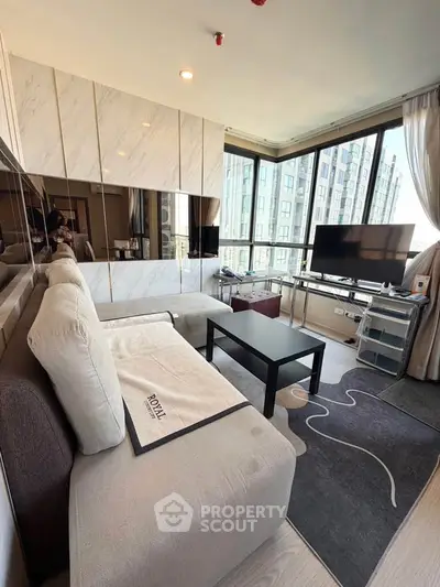 Modern living room with large windows and stylish decor in a high-rise apartment.