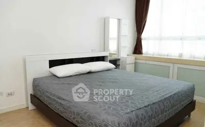 Spacious bedroom with modern furnishings and large window for natural light.