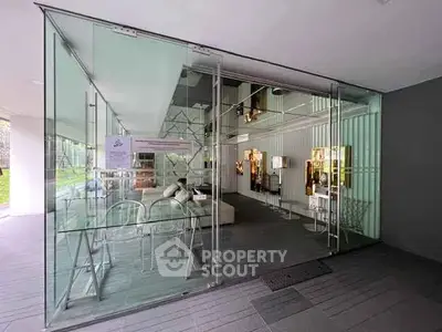 Modern glass-walled living area with stylish furniture and contemporary design.