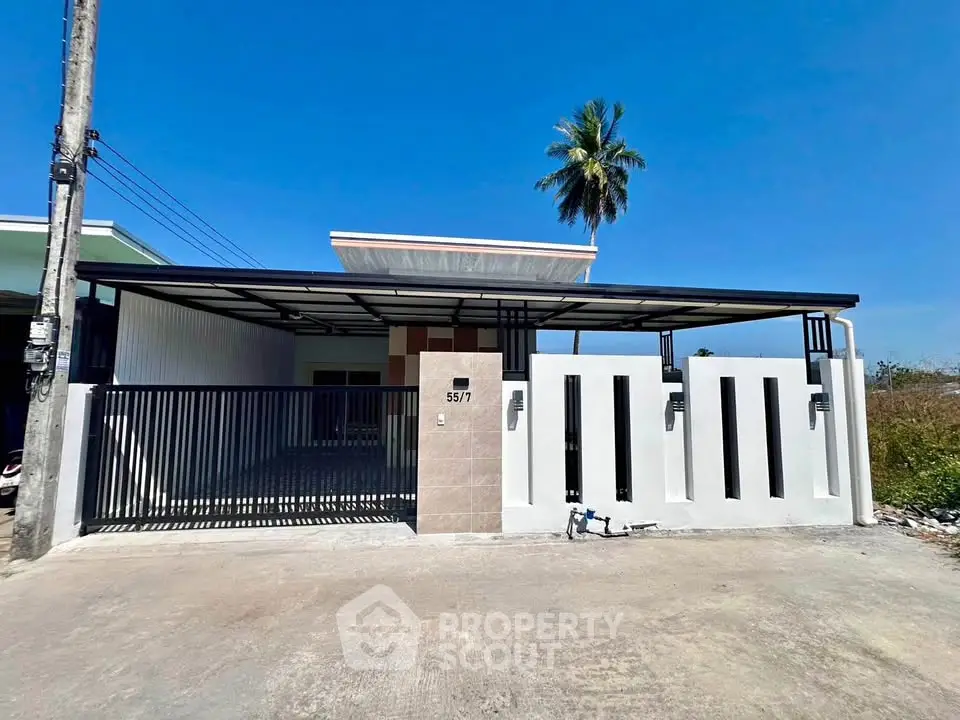Modern single-story house with sleek design and spacious driveway under clear blue sky.