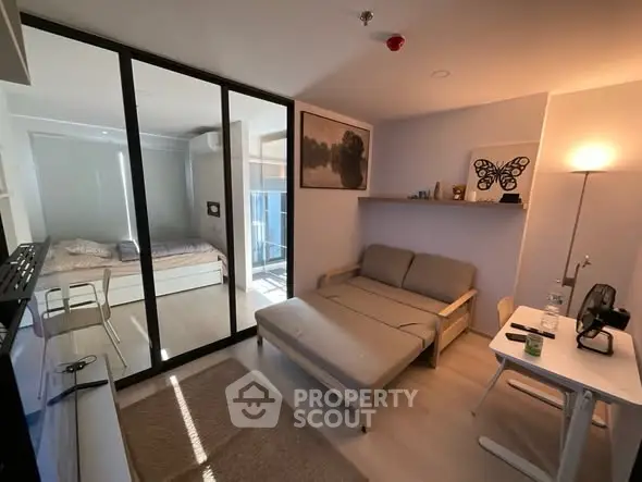 Modern studio apartment with glass partition, cozy living area, and natural light.