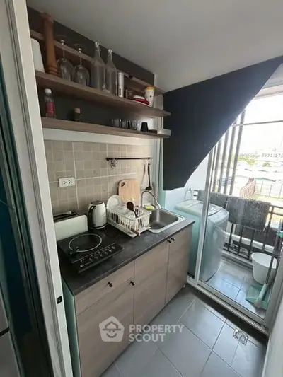 Compact kitchen with modern appliances and balcony view in urban apartment