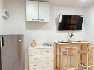 Modern kitchen with compact dining area and wall-mounted TV, perfect for cozy living.