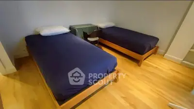 Spacious bedroom with twin beds and wooden flooring for cozy living.