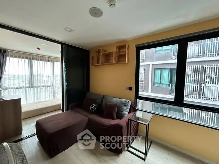 Modern living room with cozy sofa and large window view in urban apartment