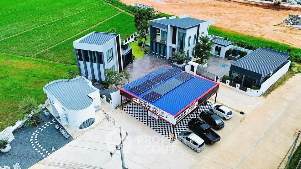 Modern residential complex with solar panels and ample parking in a serene green setting.