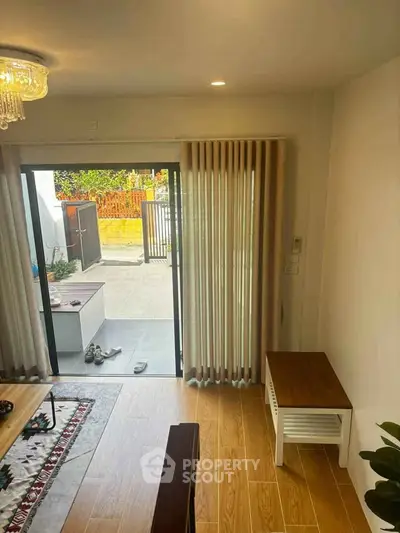 Stylish living room with wooden flooring and sliding glass doors leading to a cozy patio.