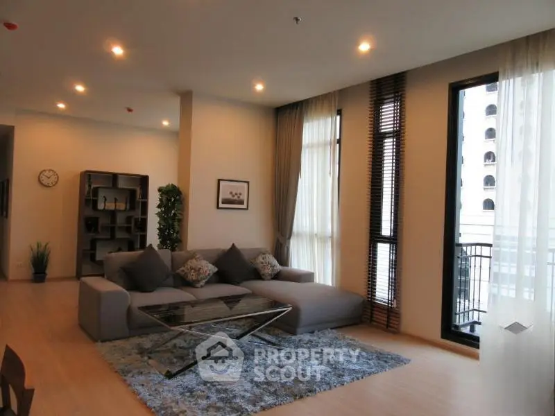 Spacious modern living room with large windows and stylish decor in a luxury apartment.