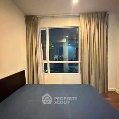 Cozy bedroom with city view through large window, perfect for urban living.