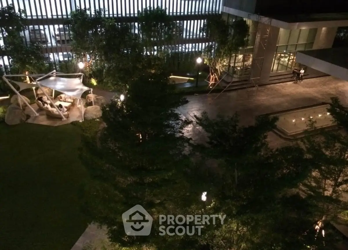 Luxurious nighttime view of modern building exterior with lush garden and ambient lighting.