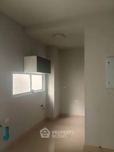 Minimalist kitchen space with window and overhead cabinet, ready for customization.
