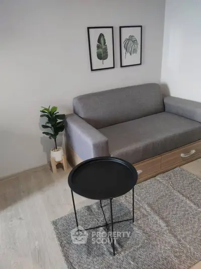 Modern living room with stylish gray sofa, minimalist decor, and chic black round table.