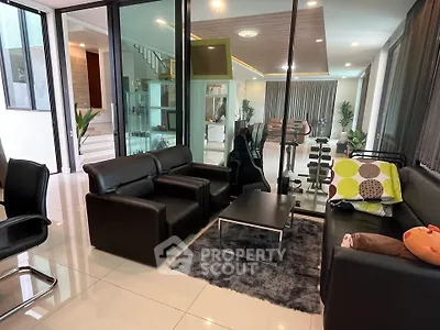 Luxurious modern living room with sleek black leather furniture and glass partitions in a spacious open layout.