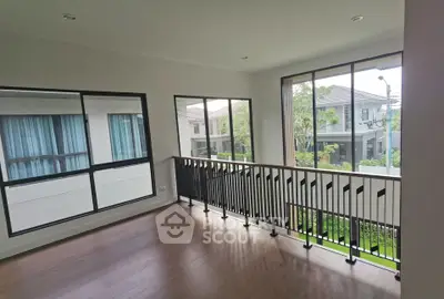 Spacious modern room with large windows and balcony overlooking lush greenery.
