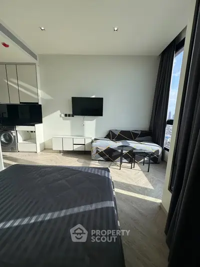 Modern studio apartment with sleek design, featuring a cozy living area, wall-mounted TV, and large windows with city views.