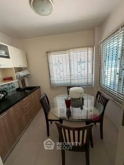 Cozy kitchen with dining area and natural light through large windows.