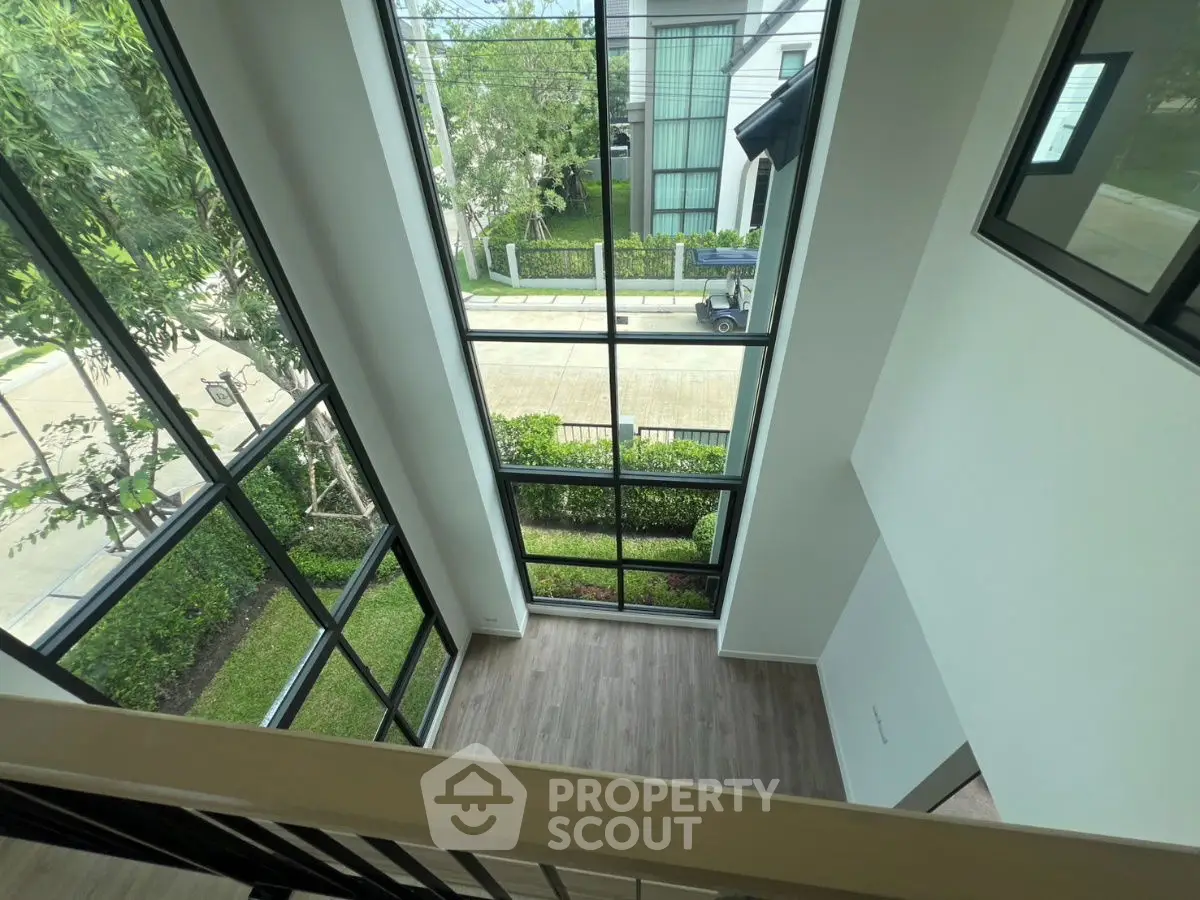 Stunning two-story window view in modern home with lush garden surroundings.