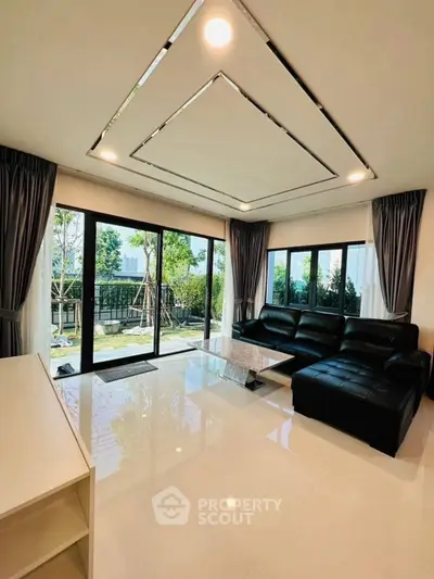 Spacious modern living room with large windows and garden view, featuring sleek black furniture and elegant decor.