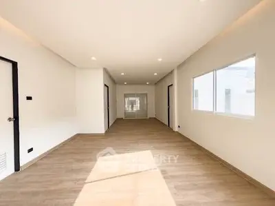 Spacious modern living room with wooden flooring and ample natural light.