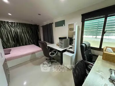 Modern bedroom with study area and large window, featuring sleek furniture and ample natural light.