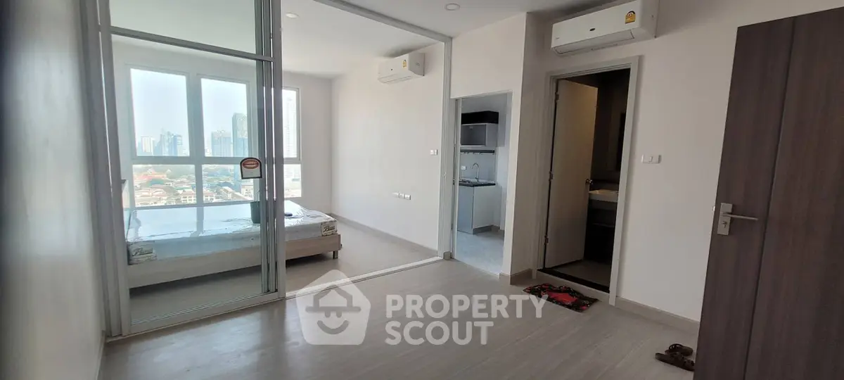 Modern apartment with city view, featuring a cozy bedroom and sleek air conditioning units.