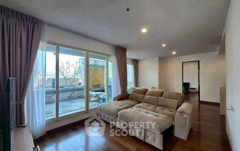 Spacious living room with large windows and cozy sofa, offering a view of the balcony.
