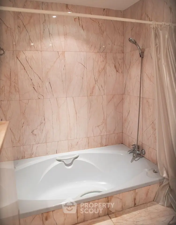 Luxurious marble-tiled bathroom with elegant bathtub and shower