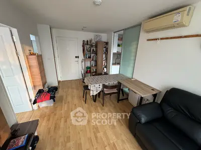 Cozy living room with wooden flooring and air conditioning, featuring a dining table and bookshelf.