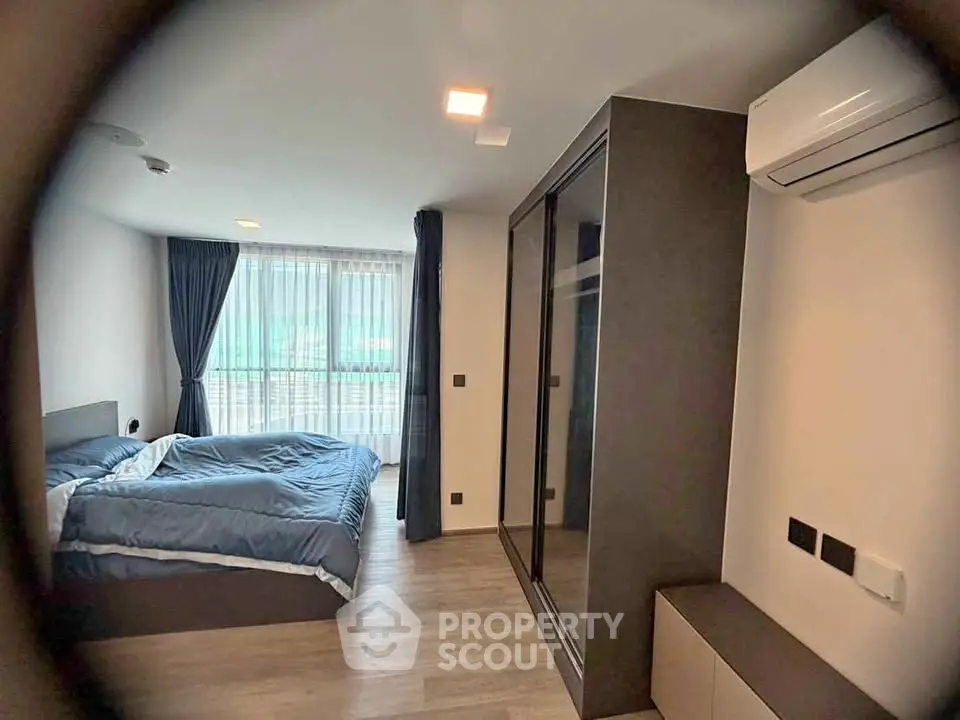 Modern bedroom with large window, air conditioning, and sleek wardrobe in a stylish apartment.