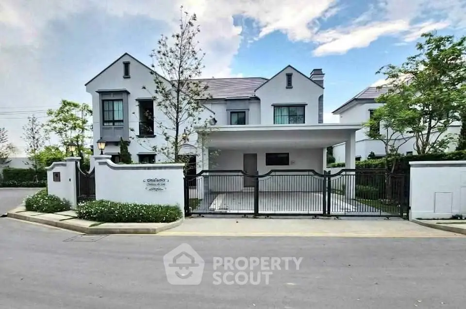 Elegant modern house with gated entrance and lush landscaping in a serene neighborhood.