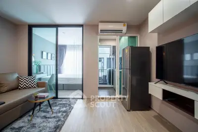 Modern living room with sleek design, featuring a cozy sofa, large TV, and open view to bedroom.