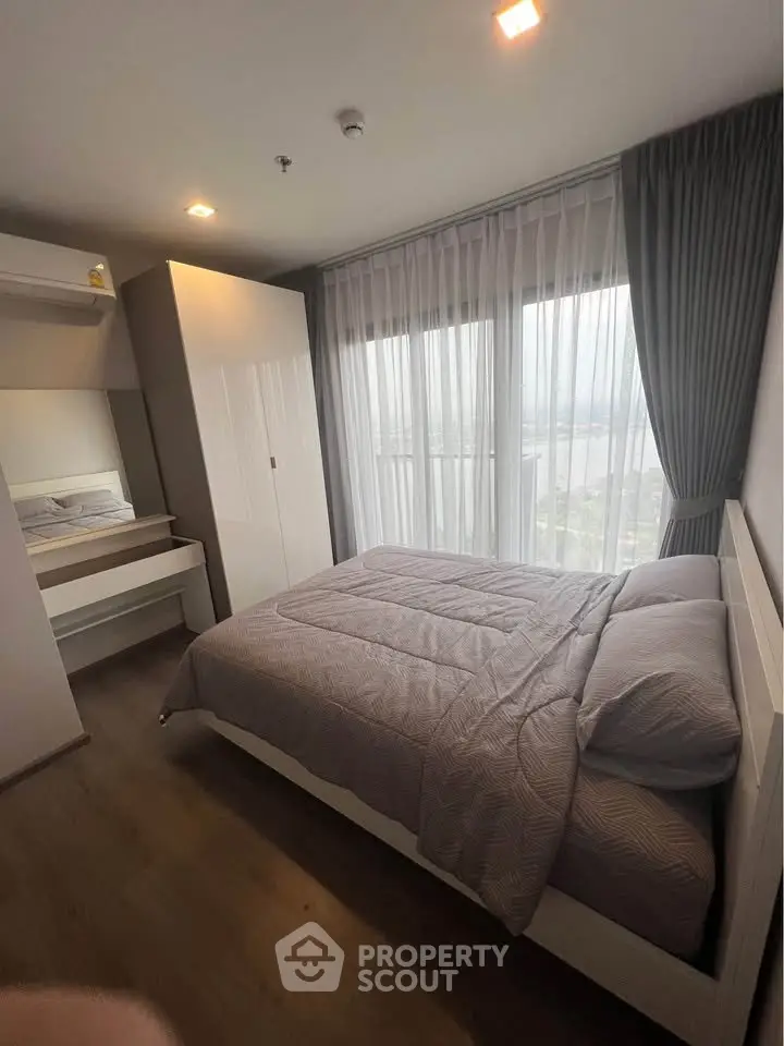 Modern bedroom with large window and stylish decor in a high-rise apartment.