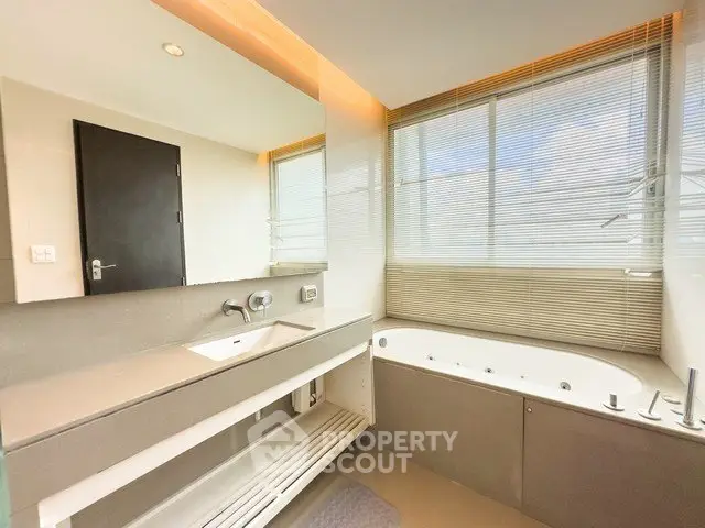 Luxurious bathroom with modern fixtures and large bathtub, featuring ample natural light.