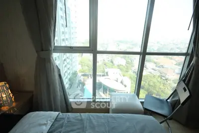 Modern bedroom with large window offering stunning city view in high-rise building.